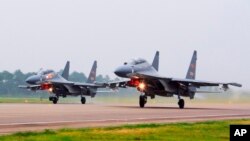 FILE - In this undated file photo released by China's Xinhua News Agency, two Chinese SU-30 fighter jets take off from an unspecified location to fly a patrol over the South China Sea.