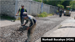 Pekerja mengaspal jalan lingkungan di wilayah Sleman, DI Yogyaakrta, dalam pekerjaan yang didanai dengan Dana Desa. (Foto: VOA/Nurhadi)