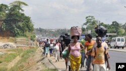 Residents of the popular district of Abobo, a suburb of Abidjan, flee fighting on February 25, 2011
