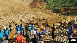 Tentara dan warga Myanmar mengevakuasi para korban tewas akibat tanah longsor di kawasan pertambangan Hpakhant, negara bagian Kachin, Minggu (22/11).