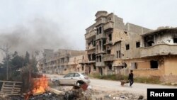 A man pulls a wheelbarrow past destroyed buildings after clashes between military forces loyal to Libya's eastern government and Islamist fighters, in Benghazi, Libya, Feb. 28, 2016. 