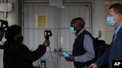 FILE - Passengers have their temperatures taken at the International O.R. Tambo Airport in Johannesburg, Oct. 1, 2020.