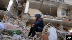 An earthquake survivor sits on debris in front of his house in a compound, which was built under the Mehr state-owned program, in Sarpol-e-Zahab in western Iran, Nov. 14, 2017.