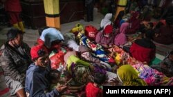 Warga berkumpul di posko pengungsian di Desa Sumber Wuluh di Lumajang pada 5 Desember 2021, pasca erupsi Gunung Semeru yang menewaskan sedikitnya 14 orang. Foto: AFP/Juni Kriswanto)