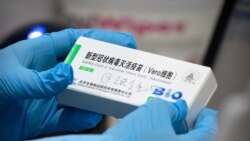 FILE - A medical worker holds a package for a Sinopharm vaccine at a vaccination facility in Beijing, Jan. 15, 2021.