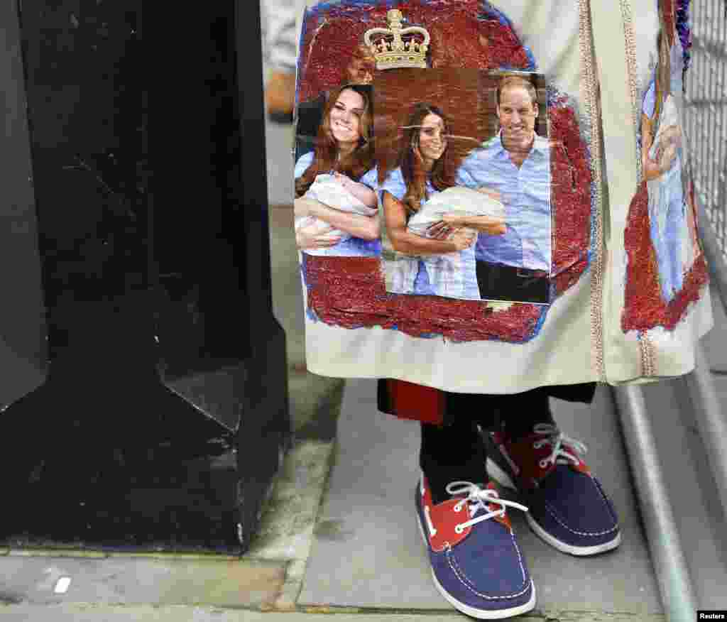 Seorang penggemar keluarga kerajaan memakai jaket bergambar Pangeran George dan kedua orangtuanya.