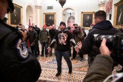 A supporter of President Donald Trump confronts police as Trump supporters demonstrate on the second floor of the U.S. Capitol near the entrance to the Senate after breaching security defenses, in Washington, Jan. 6, 2021.
