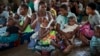 FILE - Women wait to have their children vaccinated against malaria wait at an inoculation site in the Malawi village of Tomali, Dec. 11, 2019.