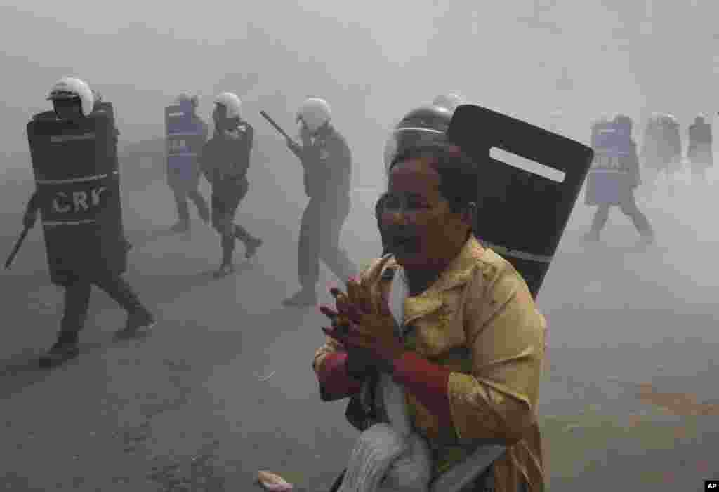 Seorang demonstran menjauh dari polisi anti huru hara yang menembakkan gas air mata pada demo di Phnom Penh, 27 Januari 2014.