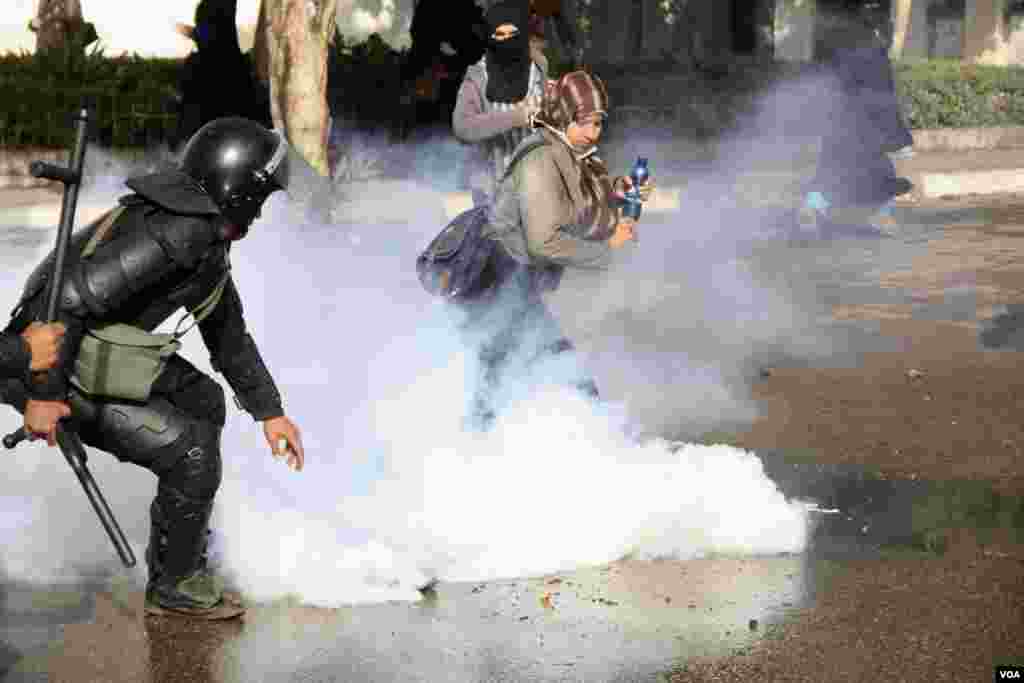 Women and police dodge tear gas during a protest at Al-Azhar University in Cairo, Dec. 11, 2013. (Hamada Elrasam for VOA)