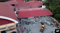 Para petugas terus melanjutkan pencarian korban di antara reruntuhan gedung yang ambruk akibat digoncang gempa di kota Porac, provinsi Pampanga, utara Filipina, 22 April 2019. 