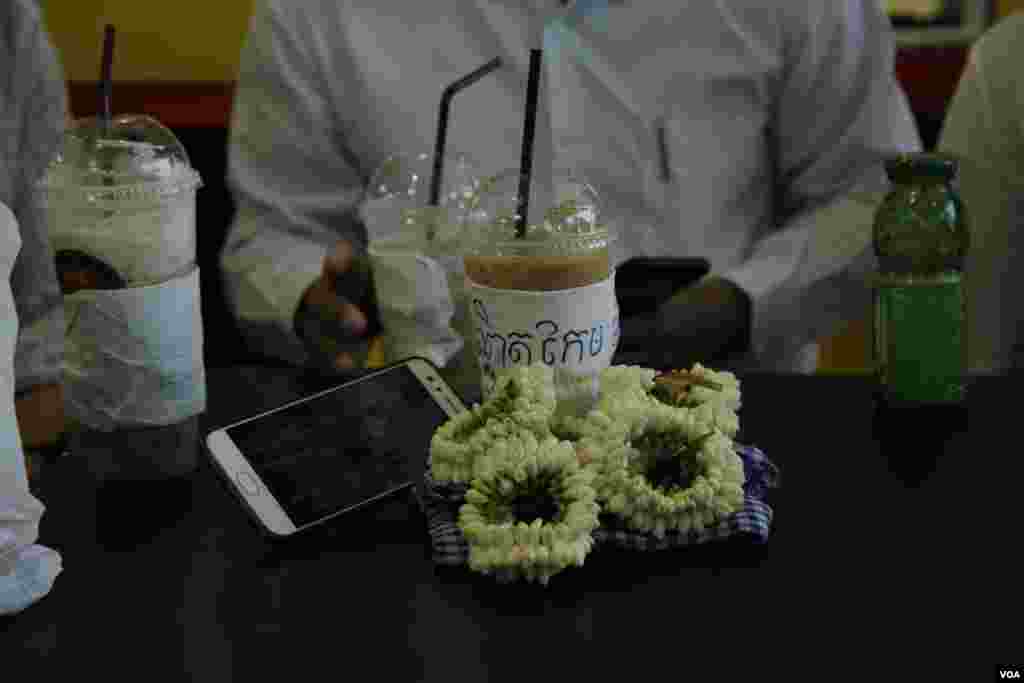 កម្រងផ្កាម្លិះនិងកាហ្វេទឹកដោះទឹកកក ដែលមានបិទឈ្មោះលោក កែម ឡី ត្រូវបានអ្នកមានសមានចិត្តដាក់នៅលើតុ កាលពីថ្ងៃទី១០ ខែកក្កដា ឆ្នាំ២០១៩ ក្នុងហាងលក់ទំនិញទីដែលលោកត្រូវបានគេបាញ់ស្លាប់ កាលពីឆ្នាំ២០១៦។ (អូន ឆេងប៉រ)