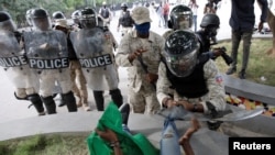 A Haitian National Police (PNH) officer pushes a protestor during clashes at a demonstration demanding the resignation of Haiti's President Jovenel Moise, at the 217th anniversary of the Battle of Vertieres, the last major battle of Haitian independence.