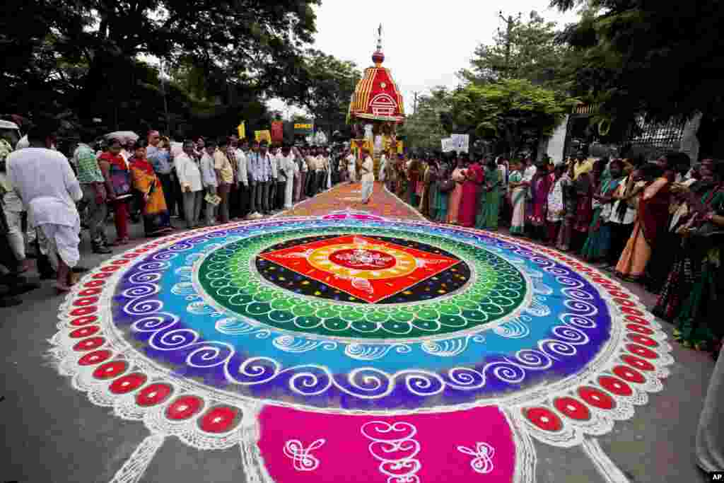 Umat ​​Hindu berdiri di sekitar karya seni tradisional yang terbuat dari bubuk berwarna selama festival tahunan Rath Yatra di Hyderabad, India.