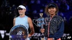 Japan's Naomi Osaka, right, holds the Daphne Akhurst Memorial Cup defeating American Jennifer Brady, left, in the women's singles final at the Australian Open tennis championship in Melbourne, Australia, Feb. 20, 2021.