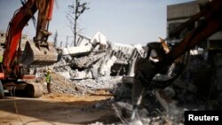 Palestinian workers clear the rubble of a school that witnesses said was destroyed by Israeli shelling during the most recent conflict between Israel and Hamas, in the east of Gaza City, Dec. 3, 2014.