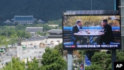 A TV screen shows a photo of South Korean President Moon Jae-in and North Korean leader Kim Jong UN, right, to advertise upcoming Seoul Defense Dialogue in Seoul, South Korea, Sept. 5, 2018. The sign read: "Peace on the Korea Peninsula."