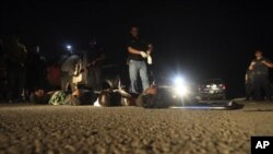 Police and forensic workers stand near the bodies of five dead men after they were left on a highway on the outskirts of Morelia, June 8, 2011