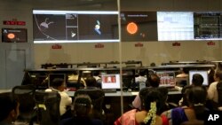 Para ilmuwan Organisasi Riset Antariksa India (ISRO) menonton grafik yang menjelaskan Misi Pengorbit Mars di kompleks kantor mereka di Bangalore, India (24/9). (AP/Aijaz Rahi)