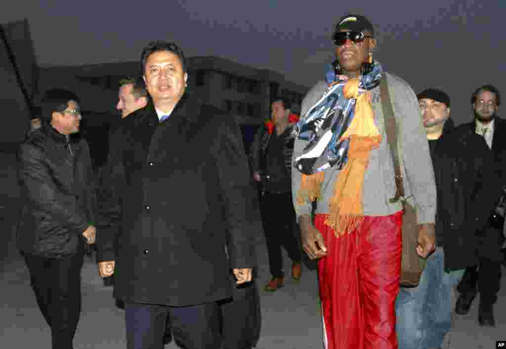 Mantan bintang bola basket NBA Dennis Rodman berjalan bersama Wakil Menteri Olahraga Korea Utara Son Kwang Ho, saat Rodman tiba di bandar udara internasional Pyongyang, Korea Utara (19/12). (AP/Kim Kwang Hyon)