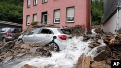 Mobil tertutup dengan puing-puing yang terbawa oleh banjir sungai 'Nahma' di Hagen, Jerman, Kamis, 15 Juli 2021. (AP Photo/Martin Meissner)
