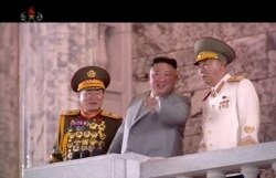 In this image made from video broadcast by North Korea's KRT, North Korean leader Kim Jong Un, center, watches a military parade marking the 75th anniversary of the country's ruling Workers' party, in Pyongyang, Oct. 10, 2020.