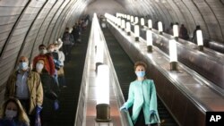 People wearing face masks and gloves to protect against coronavirus observe social distancing guidelines as they go down the subway on the escalator in Moscow, Russia, May 12, 2020.