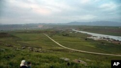 FILE - A woman and child sit on a hill overlooking the Euphrates River in Derik, Syria, May 1, 2019. Turkey wants to establish a safe zone east of the Euphrates River in Syria.