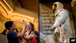 Some of the first visitors to view Neil Armstrong's Apollo 11 spacesuit after it is unveiled at the Smithsonian's National Air and Space Museum in Washington, July 16, 2019, take photos of the suit.