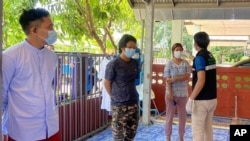 In this photo released by the San Sai District Administrative Office, a Thai officer checks the temperature of journalists working for Democratic Voice of Burma, at San Sai District in Chiang Mai province north of Thailand, May 9, 2021. 