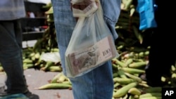 A vendor holds the bank notes in a plastic bag, at a market in Caracas, Venezuela, Sept. 23, 2017. 