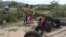 Kea Teav and her family stand in front of a two-wheeled tractor that was burnt down by a member of the Wildlife Alliance team in Krakor district, Pursat province, Cambodia, August 5, 2020. (Sun Narin/VOA Khmer)