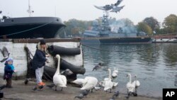Olga Zyukina and her son Yura feed swans on the pier at the Russian Baltic Fleet base of Baltiysk, Russia, Oct. 19, 2016. Despite mounting tensions between Russia and NATO, Russians seem largely oblivious to a threat of a new Cold War.