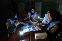 Afghan election workers count ballots in the presidential elections at a polling station in Kabul, Afghanistan, Sept. 28, 2019.