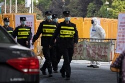 Chinese police officers march past a checkpoint around the Wuhan Central Hospital in Wuhan in central China's Hubei province, April 4, 2020.