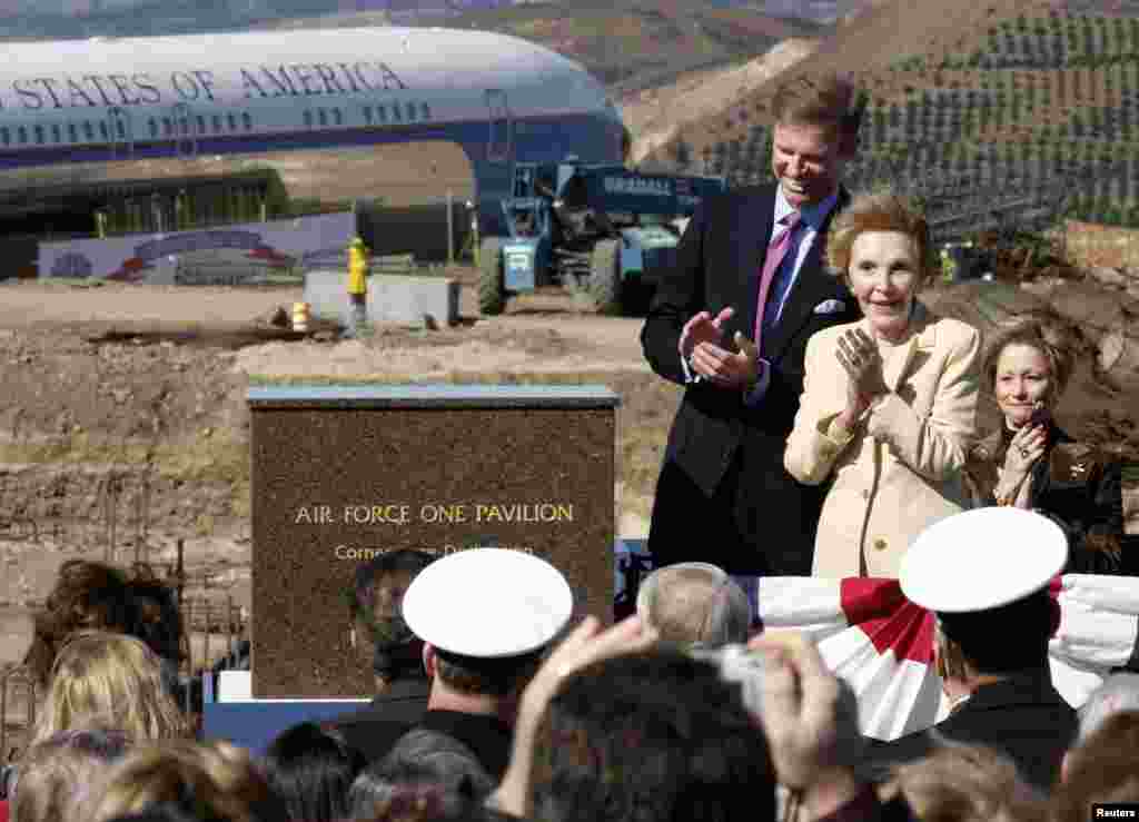Former U.S. first lady Nancy Reagan applauds after unveiling the cornerstone for a new pavilion to house the former Air Force One (background L), during a dedication ceremony at the Ronald Reagan Presidential Library in Simi Valley, California, Feb. 6, 2004.