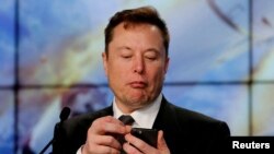 FILE PHOTO: Elon Musk looks at his mobile phone