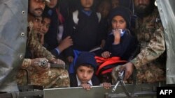 Tentara Pakistan mengangkut anak-anak sekolah yang diselamatkan dari lokasi serangan Taliban di sebuah sekolah di Peshawar (16/12). (AFP/A. Majeed)