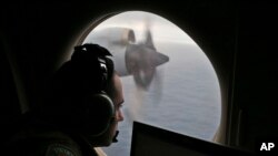 FILE - A flight officer aboard a Royal Australian Air Force plane, searches for signs of missing Malaysia Airlines Flight MH370 in the southern Indian Ocean off Australia.