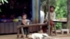 Children sit near a minefield outside their home in the northwestern Cambodian province of Battambang, one of the most heavily-mined in the country