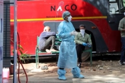 FILE - An Indian doctor stand near a disinfectant tunnel outside a hospital where most COVID-19 patients are being treated in Jammu, India, during lockdown in Jammu, India, April.6, 2020.