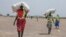 Women walk back to their homes after receiving food distributed by ICRC at a site in Leer County region of South Sudan, Tuesday, April 11, 2017. 