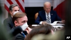 White House national security adviser Jake Sullivan, front, Secretary of State Antony Blinken, background-left, attend a meeting with President Joe Biden, right, in the Roosevelt Room of the White House, in Washington, March 1, 2021. 