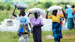 Des femmes transportent des sacs de maïs lors d'une distribution d'aide alimentaire à Mudzi, à environ 230 kilomètres au nord-est de la capitale Harare, Zimbabwe, le 20 février 2020.