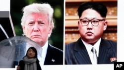 A woman walks by a huge screen showing U.S. President Donald Trump, left, and North Korea's leader Kim Jong Un, in Tokyo, Friday, March 9, 2018. After a year of threats and insults, Trump accepted an invitation to meet with Kim for talks about the North’s nuclear program. (AP Photo/Koji Sasahara)