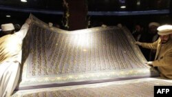 Xattot Muhammad Sobir Yoqutiy dunyoning eng katta Qur'on nusxasini varaqlamoqda. Ushbu Qur'onni yozib chiqish uchun xattot va uning to'qqiz shogirdi besh yil vaqt sarflagan. Kobul, Afg'oniston (AP Photo/Musadeq Sadeq).