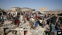 FILE - People gather on the rubble of shops destroyed by a Saudi-led airstrike at a market in Sana'a, Yemen, July 20, 2015. 