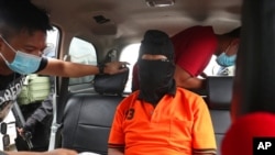 Police officers escort suspected militant Zulkarnaen, center, who is also known as Aris Sumarsono, upon arrival at Soekarno-Hatta International Airport in Tangerang, Indonesia, Dec. 16, 2020.