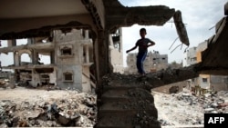 A Palestinian boy plays amid the rubble of his family's former house, which was destroyed in the 2014 war between Israel and Hamas militants, in the Eastern Gaza City Shujaiya neighborhood, May 11, 2015.