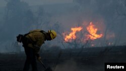 A firefighter works to put out hot spots on a fast-moving wind-driven wildfire in Orange, California, Oct. 9, 2017. 